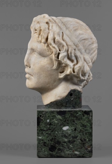 Head of Alexander the Great, unknown Roman workshop. Alexander III the Great King of Macedonia; 356–323 BC, male portrait, Roman sculpture, Roman copy from a Greek original, head of a young man turned clearly to the left in a pathetic manner. The head is reflected at the base of the neck. Oval face with unemphasized skeletal structure; prominent mouth with slightly parted lips; straight nose, reflected at the tip; almond-shaped, deep-set eyes with strongly projecting, expressive eyebrows. Forehead flat, low, covered with lush locks of hair. Hairstyle of loosely arranged, slightly curled locks; above the forehead, shifted off-axis to the right, a lock of hair radiates outward, slightly raised and clearly different from the others. At the back, hair arranged in wavy locks, with only the lower part freely arranged. Dated 140–160 AD previously dated 150–160 AD. Findspot: Rome via Nomentana. Sculpture; height 19.8 cm, width 16.1 cm, depth 14.2 cm, weight 8.5 kg., A sculpted head in a side p...