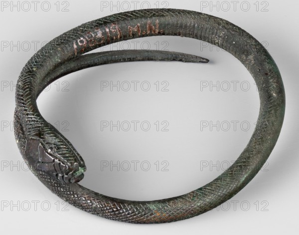 Snake bracelet, snakes, bracelets, 1st century BC, Italy, jewelry; height 2.3 cm, width 9.7 cm, depth 9 cm, weight 174 g;, A coiled object shaped like a snake with textured, scaled surface in dark green and brown tones, with areas of lighter green patina and small orange-brown spots; the head is more detailed with ridged patterns and a darker, almost black section near the mouth, and the body curves into a loose spiral on a pale gray background.