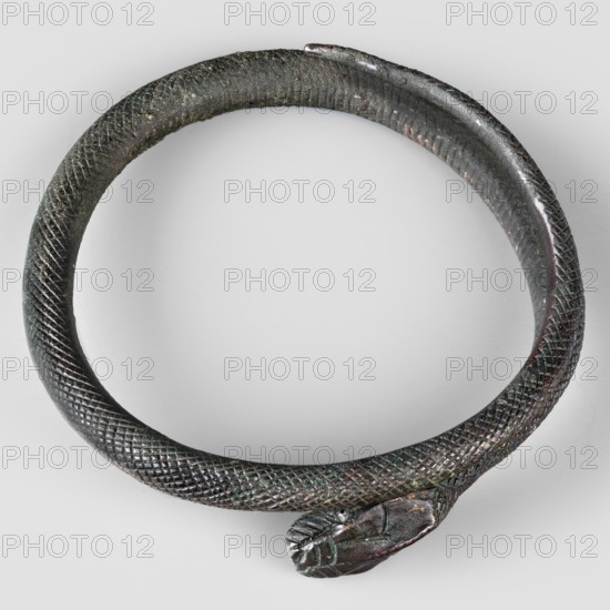 Snake bracelet, snakes, bracelets, 1st century BC, Italy, jewelry; height 2.3 cm, width 9.7 cm, depth 9 cm, weight 174 g, A circular metal object shaped like a coiled snake with textured, scale-like patterning along its length and a stylized head at one end, shown on a light gray background; visible colors include dark brown, greenish patina, and hints of black and reddish tones.