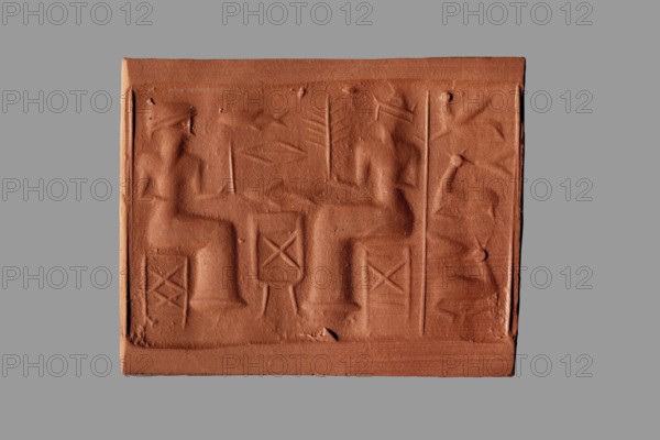 Cylinder seal with a banquet scene, unknown Assyrian workshop. The cylinder's surface is engraved with a banquet scene featuring two figures seated on either side of a sacrificial table. Above the table are two fish separated by the symbol of the goddess Ishtar — a rhombus with a line in the middle. The figures wear long smooth robes and oval-topped hats with high/wide brims, each holding a palm branch in one hand while the other arm is bent at the elbow at waist level. The vertical field behind both figures is demarcated by two vertical lines and contains three animals arranged one above the other: a winged creature on top and two antelopes lying with legs tucked under below. Iconography includes banquet scenes, rhombuses, palm branches, stools, animals antelopes, fish, and Ishtar. Eastern Gallic scene. 2nd half of the 2nd millennium BC; Middle Assyrian period, Northern Mesopotamia Assyria. Seal; height 4.2 cm, width 1.8 cm, diameter 0.3 cm opening; narrows in the middle to 0.2 cm., A...