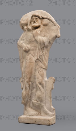 Figurine of Hermes Cryophorus, Hermes mythology, Greek deity. Statuette of Hermes Cryophorus striding to the right, carrying a goat on his back. His legs are decorated with wings. His face is framed by stubble and a pointed beard. With his left hand, he holds the goat's hind leg under his chin. Depicted in a manner characteristic of the Archaic period: legs in profile, torso and head frontally. The god wears a himation draped like a shawl over his shoulders, the ends falling down the sides, and a hairstyle with curls held above his forehead. Hermes strides on an altar, his legs depicted in relief against its background. In his bent left hand he holds a caduceus. The whole is set on a small rectangular base. Date: 490–460 BC previously dated 500–490 BC. Place of origin: Boeotia. Terracotta figurine. Height 19.5 cm, width 9 cm, depth 4.5 cm, weight 0.28 kg.