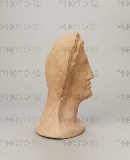 Votive female head, Female head wearing a wreath, from under which lush locks of hair curl down the sides of the face to the neck. High forehead, large eyes, deep-set in relation to the nose, slightly convex with developed eyelids and eyeballs with marked pupils. Small straight nose; narrow, slightly parted mouth with fleshy lips. Strong chin, slightly protruding forward; slim cheeks giving the face a triangular outline. 3rd–2nd century BC, Etruria; votive. Height 26 cm, width 21 cm, depth 13 cm, weight 2 kg., A sculpted bust in a warm beige clay color shown in profile facing right, with a smooth elongated neck and stylized facial features including a pronounced nose and slightly parted lips, a hood-like form covering the top and back of the head with a rougher textured ridge along its edge, subtle surface variations and small speckles in the clay, and a neutral pale gray background.