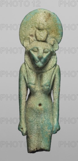 Amulet — figurine of a lion-headed goddess Sakhmet?, Figurine of the goddess Sakhmet with a lion's head topped with a solar disc with a uraeus, in a tripartite wig and a long narrow robe. The lower legs are missing, but the figure seems to be walking, with its arms lowered. On the back pillars. 664–332 BC; Late Period, Egypt. Amulet; height 5.8 cm, width 1.7 cm., A small weathered figurine with a humanoid body and an animal-like head wearing a rounded disc behind the head; the surface shows a mix of turquoise, green, pale blue, and sandy beige with areas of darker green and small lighter speckles; the figure stands upright with arms at its sides and a narrow waist, a rounded chest, and a textured collar or mane around the neck area; the head has pointed ears and a muzzle-like face with closed or simplified eyes; the disc behind the head is mottled with turquoise and beige patches and shows rough surface pitting; the lower edge of the figure is irregular and darker along the base.