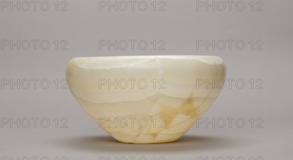 Bowl, large stone bowl with a small flat bottom, slightly flared side walls bent inward at the top and a straight rim, ca. 2686–2181 BC Old Kingdom, found at Abu Rawash, vessel, height 14 cm, width 23 cm, weight 1.35 kg, A smooth, rounded bowl with a matte surface sits on a flat surface; the bowl shows layered, banded patterns in shades of pale cream, off-white, light yellow, and soft beige with slightly darker yellowish-brown areas and subtle translucent veins, and the background and surface are a neutral light gray.