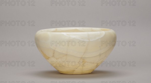 Bowl, stone vessel, large bowl with a small flat bottom, slightly flared side walls at the top bent inwards and a straight rim; Old Kingdom, ca. 2686–ca. 2181 BC; Abu Rawash; vessel; height 14 cm, width 23 cm, weight 1.35 kg, A smooth, rounded bowl with a wide opening sits on a flat surface; the bowl is predominantly creamy off-white with translucent pale yellow and beige veining and banding, showing a few subtle areas of warmer yellow and faint gray lines, and the background and surface are neutral light gray.