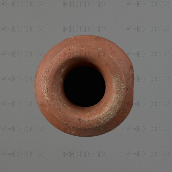 Vessel, Egyptian pottery, ceramics, clay vessel; conical-shaped vessel, widest at approximately 3/4 of its height. Quite wide, almost horizontal shoulders slightly sloping. Wide, short, funnel-shaped neck widening towards the spout. Wide spout, flat in the upper part, slightly rounded at the bottom, slightly asymmetrical. Flat, asymmetrical bottom. Surface leveled; lower part finished to approximately 2/3 of its height with a knife or similar tool. Outer surface and inner surface of rim and neck covered with a layer of dark red engobe. Vessel color dark red. Vessel complete; surface eroded in many places, numerous clay chips on the rim. Old Kingdom, ca. 2686–2181 BC; provenance Edfu. Height 16 cm; diameter 8.6 cm rim, 10.7 cm body, 4.5 cm bottom., A close-up top view of a round terracotta vessel with a wide rim and a deep dark interior, showing a weathered rough surface with patches of pale discoloration and small spots of darker tones, set against a smooth neutral gray background with...