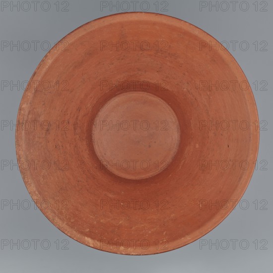 Deep bowl. Cup-shaped clay bowl with slightly convex bottom and sides arching upwards, straight flaring rim, flat on top. Made of Nile clay NB1, per Vienna System, covered with engobe mixed with red ochre and highly polished; red color. Well preserved with slight clay damage on the rim. Comparative parallels: G. Reisner Mycerinus; Giza Necropolis II, G. Brunton Qau and Badari II, types 4Q–4T — Dyn. IV–VI, C. Knoblauch late VI dynasty, J. Bourriau Umm el-Qaab, no. 85 — 4th dynasty; Old Kingdom, 5th–6th Dynasty. Dimensions: height 15.1 cm; lip diameter 27.6 cm; bottom diameter 11.8 cm; weight 1.3 kg., A top-down view of a round, shallow bowl with a wide rim and a recessed center, showing a textured, slightly worn surface in shades of terracotta and reddish-brown, placed against a smooth gray background.