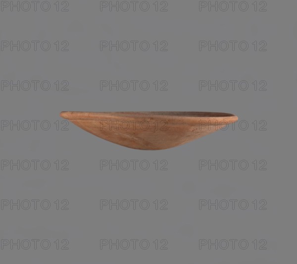 Bowl, Low bowl with a rounded bottom and a widening, rounded rim. Nile clay, fine-grained, well-fired. Smoothed surface. Formed on a slow-rotating wheel. Bowl glued together from several fragments. Dated c. 2686–2181 BC, Late Old Kingdom. From Edfu. Vessel height 4.7 cm; rim diameter 22.9 cm., A shallow, bowl-shaped terracotta object with a smooth rounded rim and a slightly convex exterior, shown against a plain gray background; the object displays earthy orange-brown and muted reddish-brown tones with subtle variations and small darker speckles in the clay.