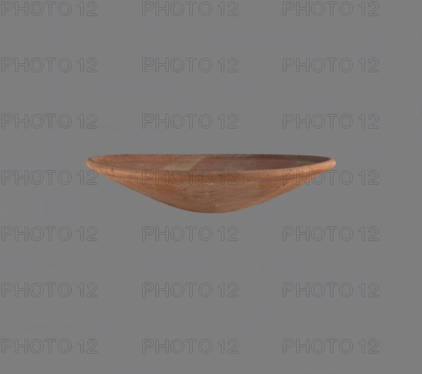 Bowl, Low bowl with a rounded bottom and a widening, rounded rim. Nile clay, fine-grained, well-fired. Smoothed surface. Formed on a slow-rotating wheel. Bowl glued together from several fragments. Old Kingdom late Old Kingdom, c. 2686–c. 2181 BC, Edfu; vessel, height 4.7 cm, diameter 22.9 cm. References: A. Reisner, A History of the Giza Necropolis, vol. I, London 1942, 4240, 13.II.67, c. 2686–c. 2181 BC., A shallow, round clay bowl with a smooth rim is centered against a plain gray background; the bowl shows earthy tones of brown, terracotta, and muted orange with subtle variations in hue and surface texture, including small speckles and faint worn areas, and its interior and exterior surfaces appear slightly uneven and matte.