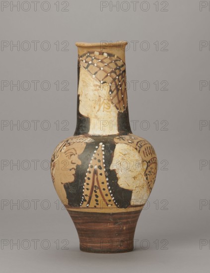 Red-figure oinochoe by the Torcop Painter, Classified Gallo-Classic Scenography; wine vessel with mythological scenes and women; 2nd half of the 4th–3rd century BC circa 300–280 BC, to be verified; Etruria place of origin; vessel; height 31.5 cm, width 16.2 cm, depth 15.6 cm, weight 0.94 kg, A painted ceramic vessel with a narrow neck and rounded body sits against a plain gray background; the vase shows a palette of tan, black, brown, white, and reddish-brown, with decorative patterns and painted human profiles around the neck and shoulder area, including a profile wearing a netlike headdress on the neck and several facing profiles on the body, dotted and lined ornamental details in white and black accenting the figures, and horizontal reddish-brown bands on the lower portion.