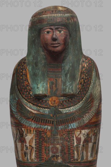 Mummy of Panepi in a cartonnage, doorkeeper of the temple of Amun Panepi; maker, Panepi ca. 945–715 BC. Richly decorated cartonnage: the deceased's wig and mask are sculpturally detailed. On the chest is a necklace with plant and geometric ornament. Below is a centrally located i3-w fetish mounted on a djed sign, behind which an inscription begins. On the sides of the fetish are winged goddesses Isis and Nephthys and the Horuses of Edfu. At the base of the fetish are depictions of Upuaut. Above the fetish is a ram-headed bird with outstretched wings Amun-Ra and Wadjet cobra, Osiris, and the three Sons of Horus. The deceased's hands are not modeled. Inscribed sacrificial formulas present; iconography includes falcons, djed pillars, necklace motif, and Taur fetish. Human remains. c. 825–715 BC; Third Intermediate Period, late 22nd–23rd Dynasty; Western Thebes. Sarcophagus/mummy cartonnage. Height 170 cm; width 40 cm; depth 29 cm; weight 37.5 kg., A painted wooden sarcophagus lid with a s...