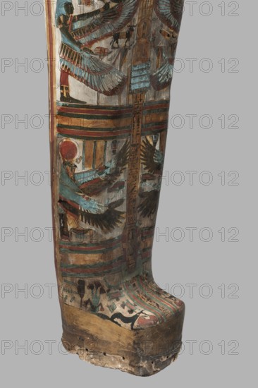Mummy of Panepi in a cartonnage, doorkeeper of the temple of Amun Panepi, Panepi ca. 945–715 BC. Richly decorated cartonnage. The deceased's wig and mask are sculpturally detailed. On the chest is a necklace with a plant and geometric ornament. Below is a centrally located i3-w fetish mounted on a djed sign, behind which an inscription begins. On the sides of the fetish are winged goddesses: Isis and Nephthys and the Horuses of Edfu. At the base of the fetish are depictions of Upuaut. Above the fetish is a depiction of a ram-headed bird with outstretched wings Amun-Ra and Wadjet cobra, Osiris, three Sons of Horus. The deceased's hands are not modeled. c. 825–715 BC; Third Intermediate Period, late 22nd–23rd Dynasty, Western Thebes. Sarcophagus/mummy cartonnage. Height 170 cm; width 40 cm; depth 29 cm; weight 37.5 kg., A painted wooden object with a curved lower edge showing a vertical panel of decorative scenes and bands, featuring a figure with a red circular headpiece and teal-blue g...