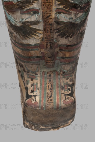 Mummy of Panepi in a cartonnage, doorkeeper of the temple of Amun Panepi, Panepi ca. 945–715 BC. Richly decorated cartonnage: the deceased's wig and mask are sculpturally detailed. On the chest is a necklace with plant and geometric ornament. Below is a centrally located i3-w fetish mounted on a djed sign, behind which an inscription begins. On the sides of the fetish are winged goddesses Isis and Nephthys and the Horuses of Edfu. At the base of the fetish are depictions of Upuaut. Above the fetish is a ram-headed bird with outstretched wings Amun-Ra and Wadjet cobra, Osiris, and three Sons of Horus. The deceased's hands are not modeled. c. 825–715 BC; Third Intermediate Period, late 22nd–23rd Dynasty. Western Thebes. Sarcophagus; mummy; cartonnage. Height 170 cm, width 40 cm, depth 29 cm, weight 37.5 kg., An upright painted wooden surface showing a stylized face and decorative motifs, with a pair of eyes near the top flanked by wing-like shapes and layered bands below; the paint palet...