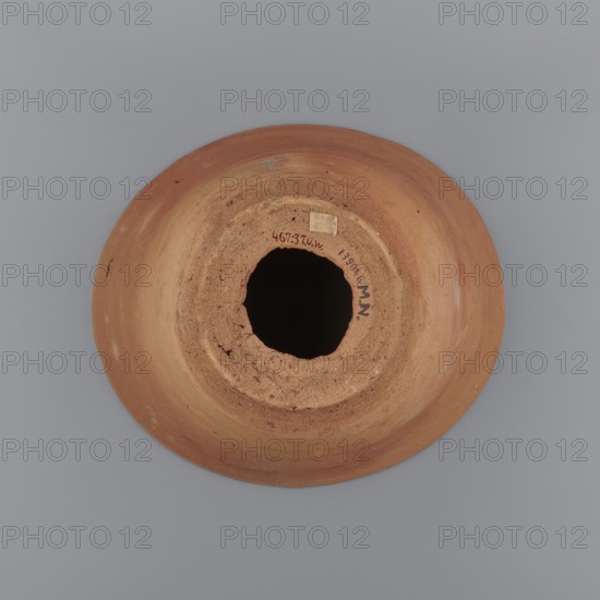 A vessel so-called flower pot for baking bread with a conical shape and a flat bottom. The shape of the vessel is irregular. A straight, flaring spout. An irregular bottom. The vessel was wheel-made from Nile clay of type NB2 according to the Vienna System classification. The surface of the vessel is level. The outer part of the vessel near the bottom and the bottom itself are finished with a knife or similar tool. There is a hole in the bottom with a diameter of approx. 6 cm, made before the vessel was fired. Vessel colour - yellowish-red. Vessel very well preserved. Irregular vessel — rim diameter: 22.3–25.2 cm; bottom diameter: 10.2–11 cm; height 17.4 cm. c. 1550–c. 1069 BC; New Kingdom, Deir el-Medina., A round terracotta object viewed from above with a central irregular hole surrounded by rough, crumbly inner edges and a smoother outer rim; the object shows variations of orange, brown, and reddish-brown tones with some lighter beige patches and small darker specks, set against a u...