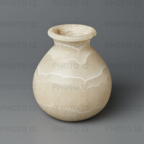 Vessel, Globular stone vessel with a short, wide neck and a large upturned spout, with a flattened bottom. New Kingdom, Egypt, ca. 1550–1069 BC. Vessel; height 14.8 cm, width 13.4 cm, weight 1.32 kg., A round pale beige vessel with a wide flared rim sits against a smooth medium gray background; the vessel shows subtle white veining and banded patterns across its curved surface, with creamy off-white and light tan tonal variations and a slightly polished finish.