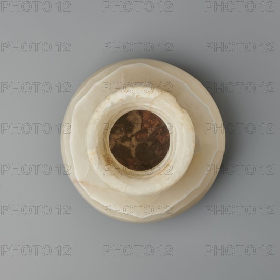 Vessel, globular vessel with a short, wide neck and a large upturned spout, with a flattened bottom; stone; New Kingdom, Egypt, ca. 1550–ca. 1069 BC; height 14.8 cm, width 13.4 cm, weight 1.32 kg., A round object with a stepped, faceted outer rim sits on a flat surface, viewed from above; the object is primarily cream and off-white with subtle beige and tan veining, and a dark, mottled interior shows brown and rust tones; the background is a smooth gray.