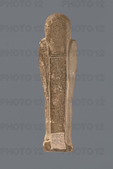 Ushabti, mummy-shaped figurine standing on a base with a pilaster at the back. Arms crossed on the chest, right folded over left; only the hands visible from under the shroud. Holds a hoe in the right hand and a pickaxe in the left; a twisted rope in the right hand supports a basket slung over the left shoulder. Engraved tools. Smooth, three-part high-domed wig; ears uncovered. Small face with large almond-shaped eyes, worn nose, mouth in a slight grimace. Long beard, slightly tapering, curled and braided at the end. Inscribed on the front of the legs, starting just below the crossed arms and extending to the toes, as a column of text bordered on both sides by vertical lines. Shabti; Ptolemaic Period, 332–30 BC, Egypt. Height 10.5 cm, width 3.9 cm., A single upright carved figure in a brown, weathered stone-like material stands against a plain gray background, showing a rounded head and a long vertical body with subtle carved lines suggesting wrapped limbs and a narrow base, with surfa...