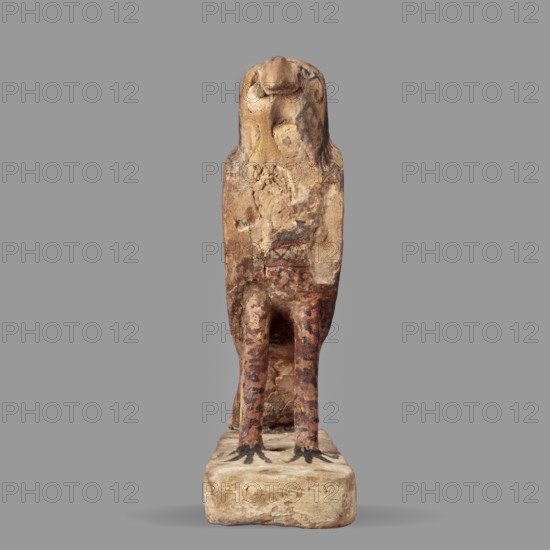 Figurine of the falcon Sokaris Horus, a painted Egyptian sculpture: a falcon stands on a thick rectangular base, tail resting on the back edge. The bird's head is slightly raised with a long curved beak; the body is elongated with wings slightly plastically defined in their upper part and merging with the tail at the lower part. The head is black on the sides and back; the front of the head is yellow with a black diagonal check. The eye is painted white and black; a white stripe encircles the neck. Wings are black and red; bird legs show red and black lines. Inscription/subject: Sokaris mythology. Date: 664–30 BC Late Period–Ptolemaic. Medium: sculpture. Dimensions: height 24.3 cm, width 20.5 cm. Creator: unknown., A weathered small statue of a bird-headed figure standing on a rectangular base, with a tall, elongated torso and a rounded head resembling a bird's beak; the surface shows worn and chipped areas with textured, rough patches and traces of painted decoration. The object displ...