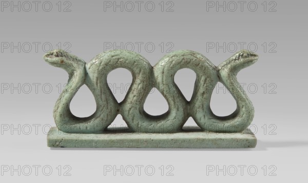 Amulet – two-headed snake, two-headed snake with vertical coils on a base, with delicately carved scales and snouts; snakes, animals; protective amulet; Egyptian art; Late Period, 664–332 BC, Egypt; amulet; height 3.3 cm, width 7 cm, depth 1.5 cm., A glazed sculptural object in a pale green color with darker green and brown speckling sits on a flat rectangular base of the same color; the main form consists of a horizontal sequence of soft, looping shapes that create three large open teardrop-like holes and end in two stylized serpent heads at each side, both heads sharing the same pale green glaze with visible texture and irregularities, all set against a neutral gray background.