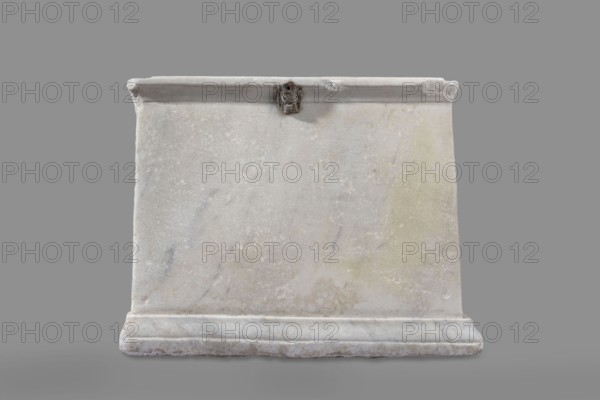Urn with a depiction of swans, unknown Roman workshop. Main plate: the urn's box is trapezoidal in shape, tapering towards the top. The urn is placed on a profiled base. The decoration of the front surface is sparse. The main part of the surface is occupied by a tabula ansata, the ears of which are decorated with palmettes. Below the inscription field are depictions of two swans in deep relief. The birds are facing each other, with strongly arched necks. They appear to be taking flight, their outstretched wings touching the inscription frame. The upper part of the urn is crowned by a profiled cornice. On the inner upper edge, a rectangular protrusion used to secure the lid is visible. Side walls: no decoration. Metal pins visible under the cornice on both sides. Lid: original missing; currently fitted with a different lid. Dated to the 2nd half of the 1st – 1st half of the 2nd century AD probably 2nd half / 3rd quarter of the 1st century AD. Roman Empire; found in Rome. Urn Roman. Weig...