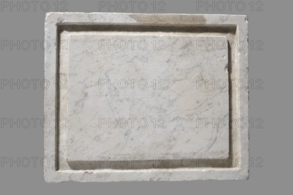 Urn with a depiction of swans, unknown Roman workshop. Main plate: the urn's box is trapezoidal, tapering toward the top and placed on a profiled base. The front is sparsely decorated; the main surface is occupied by a tabula ansata whose ears are decorated with palmettes. Below the inscription field are two swans in deep relief, facing each other with strongly arched necks and outstretched wings touching the inscription frame. The upper part is crowned by a profiled cornice; on the inner upper edge a rectangular protrusion for securing the lid is visible. Side walls: no decoration; metal pins visible under the cornice on both sides. Lid: original missing. Dated to the 2nd half of the 1st century AD probably 3rd quarter of the 1st century AD — Roman Empire 27 BC–476. Place of origin/find: Rome. Urn Roman. Weight: 45.5 kg., A square slab with a recessed rectangular panel fills the image, showing a surface of white and light gray marble with subtle veining and faint mottling, surrounded ...