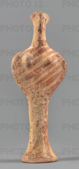 Female idol, unknown Mycenaean workshop, provenance: Königsberg; Frombork Warmian-Masurian Voivodeship — votive offering, female figurine. Female idol in the shape of the letter phi: legs form a cylindrical base widening downward skirt?, arms and torso enclosed in a circle, breasts schematically marked, long cylindrical neck, flat head. Folds of garments, facial features, and eyes simplified using brown paint or varnish; painted surface worn in places. Date: 1400–1200 BC previous dating: 1600–1100 BC. Origin: Mycenae, Greece. Typology: figurine, votive offering. Dimensions: height 12.7 cm; width 4.6 cm; depth 2.8 cm; weight 0.05 kg., A roughly shaped upright clay figure with an elongated neck and flared base, showing a rounded upper body with subtle raised forms where breasts would be, and a narrow tapering lower torso; the surface is textured and worn with patches of reddish-brown paint forming diagonal banding across the upper body and scattered mottled areas elsewhere, and the under...