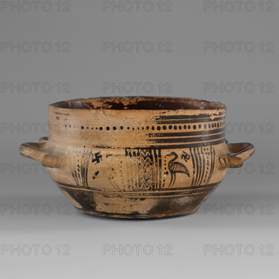 Skyphos mug with depictions of ducks, Skyphos with a profiled belly. Just below the rim are two painted bands with a delicate line. The metopes depict ducks with long necks and legs, in front of which are stylized flowers; one bird is very poorly preserved. Behind each bird's head is a swastika motif. Possibly silhouette technique. Vices placed at the maximum width of the belly. Inner surface covered with matte, faded paint. A reserved line is left a short distance from the bottom; the bottom is undecorated. Technology: Visible traces of turning. Varnish worn away in places. Clay light yellow with many inclusions. Surface shows significant abrasions and chips. Condition: Spout damaged. Visible conservation additions old glue. Clay/color notes: Black: 7.5 YT 2.5/1 black Red: 10 R 4/4 weak red Dated to ca. 725–700 BC Late Geometric period; 9th–8th century BC reference. Origin: Attica. Vessel type: skyphos. Height 9.0 cm; width 19.6 cm; depth 15 cm; weight 0.352 kg., A shallow rounded cer...
