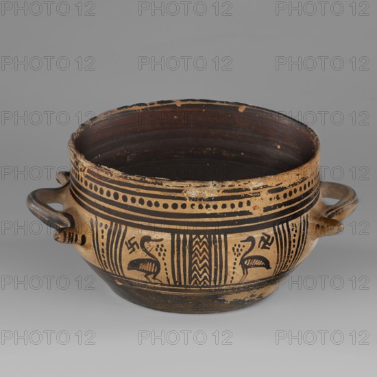 Skyphos mug with depictions of ducks. Late Geometric period, ca. 725–700 BC. Attributed to Attica. Ceramic skyphos with profiled belly; height 9.0 cm, width 19.6 cm, depth 15 cm, weight 0.352 kg. Just below the rim are two painted bands with a delicate line. Metopes depict long-necked, long-legged ducks with stylized flowers before them; one bird image is very poorly preserved. Behind each bird's head is a swastika motif. Silhouette technique possibly used. Vices placed at the maximum width of the belly. Inner surface covered with matte, faded paint; a reserved line set a short distance from the bottom, which is undecorated. Technology: Visible traces of turning. Varnish worn away in places. Clay light yellow with numerous inclusions. Surface shows significant abrasions and chips. Condition/remarks: Spout damaged. Visible conservation additions old glue. Colors approximate: Black ~ 7.5 YT 2.5/1; Red ~ 10 R 4/4. Dating and attribution notes: 725–700 BC Late Geometric; assigned 9th–8th c...