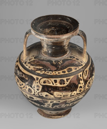 Orientalizing amphora, repossession Bytom, Greece, Corinth, early Corinthian period, 620–590 BC, amphora vessel, weight 1.730 kg, decorated with cats, images of birds, and zoomorphic decorations., A rounded ceramic vessel with a wide flaring mouth and a short neck, featuring two curved handles that attach near the rim and the shoulder; the surface shows decorative painted bands and motifs in black, brown, and beige tones with areas of worn or chipped paint revealing lighter base clay; the mouth interior is dark with visible scuffs, and the body displays flowing abstract and animal-like shapes arranged in horizontal registers; the base is slightly flared and darker in color, and the overall background behind the vessel is a neutral gray.