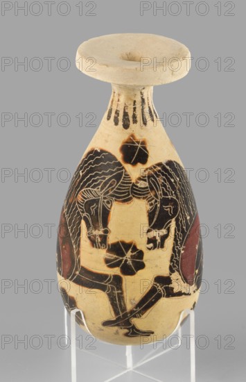 Orientalizing alabastron with depictions of horses, attributed to Corinth, c. 620–590 BC. Small aryballos/alabastron vessel height 10.0 cm with supplement; preserved original height 8.4 cm; width 4.7 cm; weight 0.066 kg. Decoration: remnants of radial ornament under the rim and on the underside; pairs of stylized horses positioned opposite each other, ending in bird-like tails, occupying the vessel’s height; very precise engraved modeling; red retouches and small filling ornaments rosettes. Technology/materials: smooth surface, yellow clay clay color 2.5 Y 7/4; black varnish 10 YR 2/1; red paint 7.5 R 4/4. Notes: reconstructed rim; visible chips and impurities., A single slender vase with a rounded body and a wide flat rim stands on a clear support against a neutral background; the vase is primarily a warm beige color with painted areas in black and dark reddish-brown, showing a stylized scene of two mirrored human figures with long wavy hair and bent legs facing each other, decorative...