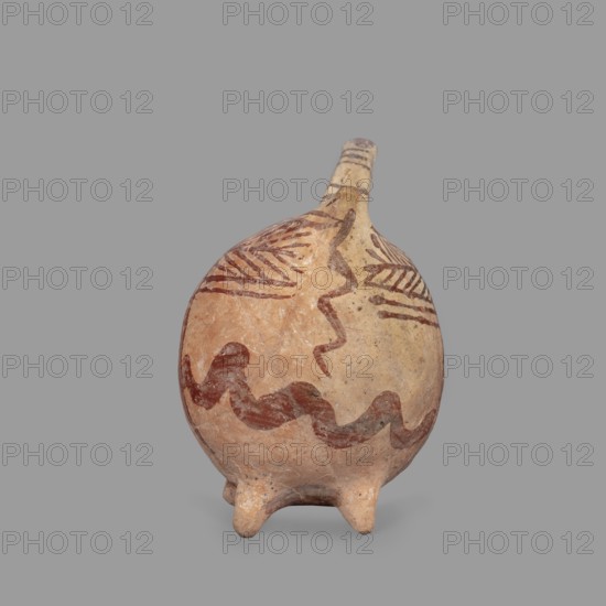 Vessel in the shape of an animal, unknown Cypriot workshop. Fantastic animal-shaped vessel with a long thin neck ending in a triangular, slightly flattened head. Eyes marked by depressions; oblong flat ears. Geometric decoration covers the entire surface: at the widest point a band of zigzag filled with a checkered pattern; herringbone stripes radiate at right angles front and back from this band; beneath these are wavy paint stripes. Series of thin lines on the neck and a hole in the front under the neck. Late Bronze Age II, 1900–1600 BC, Cyprus. Vessel; height 10.7 cm, width 12.5 cm, depth 6.8 cm., A rounded ceramic vessel with a narrow spout and a few short rounded feet, shown against a plain gray background. The vessel surface is mainly tan and light beige with areas of warm reddish-brown. There are several painted wavy and zigzag bands in a darker brown-red color encircling the body and extending toward the neck, along with a few linear hatched motifs near the shoulder. The spout ...