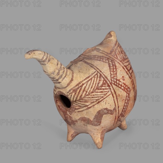 Vessel in the shape of a fantastic animal. The neck is long and thin, ending in a triangular, slightly flattened head. The eyes are marked with depressions; the ears are oblong and flat. Geometric decoration covers the entire surface. At its widest point the body is surrounded by a band consisting of a zigzag band covered with a checkered pattern; from this band herringbone stripes radiate at right angles to front and back. Beneath these are wavy stripes of paint. A series of thin lines on the neck; a hole in the front under the neck. Unknown Cypriot workshop, 1900–1600 BC Late Bronze Age II. Terracotta vessel, height 10.7 cm, width 12.5 cm, depth 6.8 cm., A pottery vessel with a rounded body and a protruding spout, standing on a few short conical legs, with a small circular opening on one side; the surface shows painted linear and geometric patterns including diagonal hatchings and curved bands in reddish-brown on a beige clay background, and the spout bears similar reddish-brown stri...