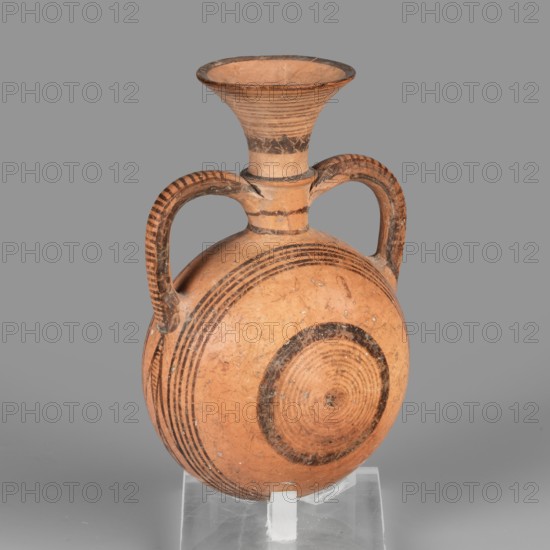 Bottle amphoriskos, Amphora with a round, slightly flattened flask-like belly. Brown-black decoration of concentric circles of varying thickness on the belly, horizontal lines on the rim, and a fine zigzag. Geometric motifs; Cypriot pottery. 1050–750 BC Cypriot–Geometric Period, Cyprus. Vessel. Height 10.4 cm; width 6.7 cm., A ceramic vessel with a rounded, flattened body and a flared neck, supported on a clear stand, shown against a gray background; the vessel is primarily terracotta orange with darker brown painted concentric circular bands on the body and neck, and darker brown striped decoration along the curved double handles; the surface shows some wear and small lighter speckles.