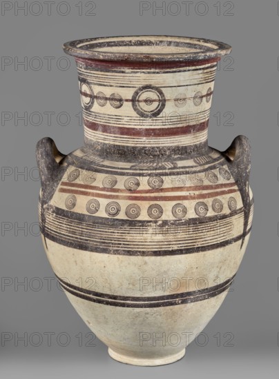 Amphora, unknown Cypriot workshop, Cypriot pottery, Amphora with a low foot, wide neck, and upturned vices. Rounded belly. Surface covered with geometric decoration emphasizing the structure of the vessel. Decoration composed of concentric bands and circles. 850–700 BC Cypriot–Archaic Period I. Cyprus, vessel, height 54 cm, width 35 cm, weight 7.40 kg., A large ceramic vessel with a rounded body, a wide flaring neck, and two loop handles, decorated with concentric circle motifs and horizontal banding in black and reddish-brown on an off-white or cream ground; the neck and shoulder show several parallel thin black lines and a few broader reddish-brown bands, with rows of circular target-like motifs in black; the handles are dark and worn, showing textured surface with darker gray or black coloration; the lower body has broad horizontal black bands and a slightly mottled off-white surface with areas of light tan discoloration; the rim interior appears darker with black and cream rings, a...