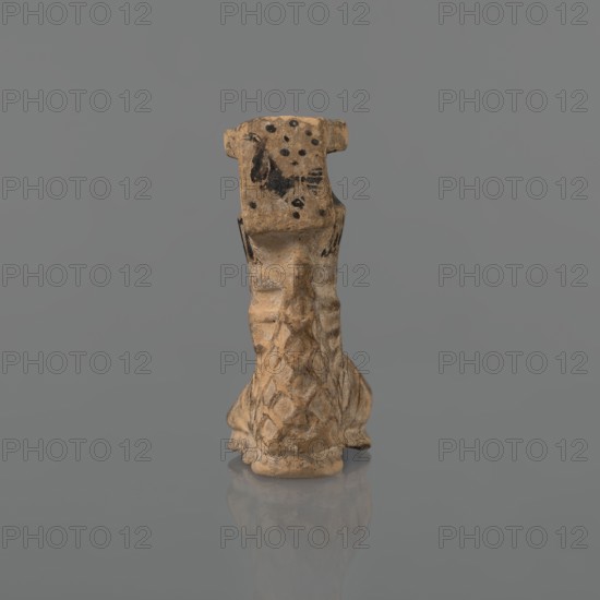 Foot-shaped aryballos, Ionian workshop, aryballos, antique vessel. Yellow-orange clay with mica; matte black engobe on the surface. Aryballos in the shape of a foot shod in a sandal with a thick sole connected to braided leather straps. The foot ends above the ankle and merges into a narrow neck terminating in an outward-turned rim, decorated from above with radiating lines. A wide, ribbon-like handle is attached vertically to the spout, on which there is an image of a rooster surrounded by dots. Preservation condition: the front part of the foot is filled with plaster. Late 6th–early 5th century BC. Ionia, Turkey/Greece., A small sculpted object resembling a stylized animal or creature sits upright against a plain background; the object is primarily tan with darker brown and black patches and spots, and it shows textured, carved surfaces with a pattern of scales or diamond shapes on its lower portion and smoother, worn areas on its upper portion, with visible irregularities and small ...