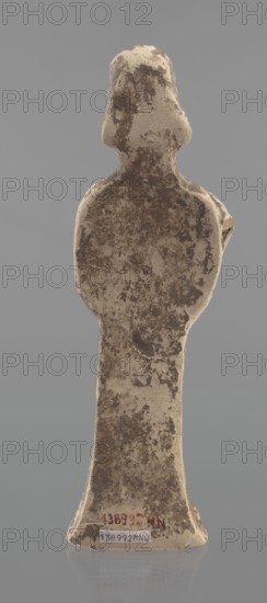 Terracotta figurine of a woman, unknown Boeotian workshop. Female terracotta, mold-pressed figurine. Standing woman in a long chiton. Head set on a thick neck. Oval face with a large nose and almond-shaped eyes. Arms bent at the elbows, forearms raised with hands pressed against the shoulders. Right hand holds a cylindrical object probably a fragment of a longer element. Traces of brown and red polychrome. Condition: left hand broken off, surface worn. Ca. 550 BC. Boeotia. Figurine; height 23 cm, width 7 cm., A standing, human-shaped figure viewed from the back with a rounded head and broad shoulders tapering to a flared base, showing a worn, mottled surface in shades of beige and brown against a smooth gray background.