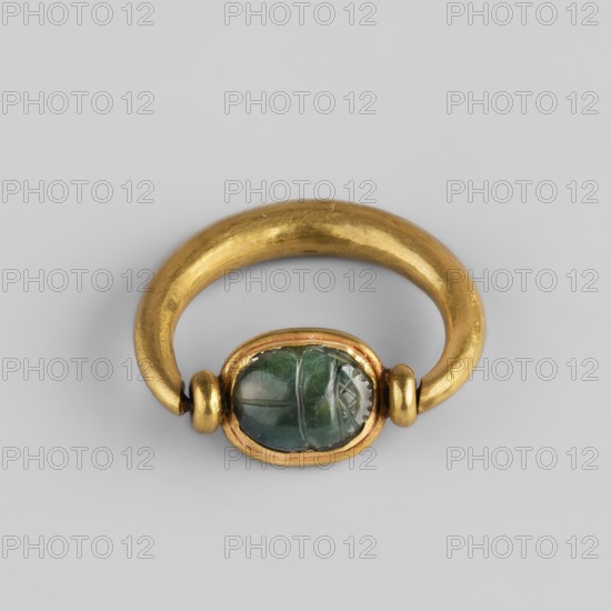 Ring with a scarab and a cryptogram of Amun; Amun mythology, ankh iconography, plant decorations; jewelry, Egyptian art, goldsmithery. The underside of the base is engraved: a bull visible in right profile with the ankh sign above it; in front of the bull on the right side is a tuft of vegetation; at the bottom, a double horizontal line interrupted by three lines mat — probably a cryptogram of the name Amun. Scarab amulet ring, c. 1550–c. 1295 BC; New Kingdom, 18th Dynasty, Egypt., A gold ring with a rounded band and a smooth, slightly irregular surface holds an oval green stone set in a gold bezel; the stone shows variations of green with lighter and darker areas and internal lines, and there are small gold beads flanking the bezel, all shown against a light gray background.