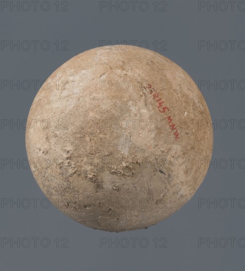 Globular vessel, unknown Northern Mesopotamian workshop, Early Jazira III period ca. 2600–ca. 2350 BC. A globular vessel whose body rises about 3/4 of its height into sloping arms, from which arises a low, narrow neck terminating in a thickened, flared rim. The transition from the body to the arms is emphasized by a shallow, wide horizontal groove. Function: vessel for oils and ointments; vice-free vessel., globular vessel; Early Dynastic III period. Origin: Northern Mesopotamia Al-Jazira, Khabur basin, Tell Jassa el Gharbi, Syria. Dimensions: height 10 cm, width 9.7 cm., A roughly spherical object with a textured, uneven surface in shades of beige, tan, and light brown floating against a solid gray background; the surface shows areas of lighter off-white patches and some darker brown spots, with visible rough patches and small indentations across the sphere.