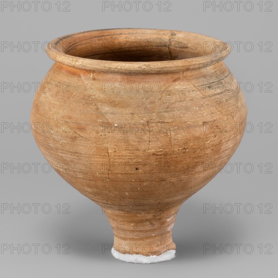 Beaker, unknown Northern Mesopotamian workshop; stemmed beaker; clay; Beaker with a bulging bowl, with an upturned flat and narrow rim, set on a low cylindrical stem terminating in a small foot damaged. Horizontal traces of polishing on the surface. 1st half of the 3rd millennium BC; Early Jazira III period ca. 2600–ca. 2350 BC. Tell Jassa el Gharbi North-Eastern Syria, Northern Mesopotamia Khabur Basin. Vessel; height 11.5 cm, width 11.6 cm, weight 264 g., A rounded earthenware vessel with a wide flared rim tapering into a narrow rounded base, made of weathered clay showing a range of tan, light brown, reddish-brown, and beige tones with subtle horizontal striations and surface imperfections; the interior appears darker with similar brown hues, and there is a small area of white material at the very bottom supporting the base, all set against a plain neutral gray background.