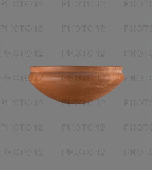 Medum-type bowl, Egyptian ceramics; Medum-type bowl with characteristic carination under the rim. Rounded bottom. Straight, slightly flaring rim. Narrow, sloping shoulders. Diameter of the rim is smaller than the diameter of the vessel's shoulders. Nile clay, light red, well fired. Surface leveled, covered with a layer of engobe and polished. On the outside of the bottom part is a hieroglyphic sign in the shape of a bird, probably the letter m. Vessel color red. Complete, very well preserved. Comparative material: Junker, Giza I, pl. XII no. 16; Reisner, A History of the Giza Necropolis, vol. I, fig. 282. ca. 2686–ca. 2181 BC; Old Kingdom; Edfu; vessel height 8.9 cm, diameter 20.9 cm rim, diameter 21.5 cm shoulders., A single rounded bowl-shaped object in a terracotta orange color is centered against a flat gray background, showing a smooth rim and gently curved sides with some lighter worn areas and subtle surface texture.