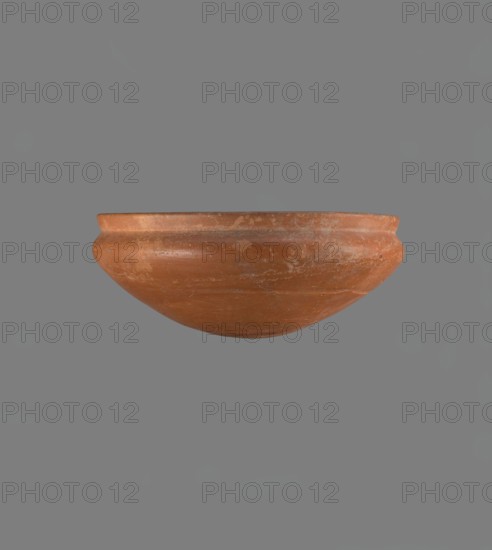 Medum-type bowl, Egyptian ceramic, Medum-type bowl with characteristic carination under the rim. Rounded bottom. Straight, slightly flaring rim. Narrow, sloping shoulders. Diameter of the rim is smaller than the diameter of the shoulders. Nile clay, light red, well fired. Surface leveled, covered with engobe and polished. On the outside of the bottom is a hieroglyphic sign in the shape of a bird, probably the letter m. Vessel color red. Complete, very well preserved. Comparative material: Junker, Giza I, pl. XII no. 16; Reisner, History of Giza Necropolis, vol. I, fig. 282. Old Kingdom, ca. 2686–2181 BC. Height 8.9 cm; rim diameter 20.9 cm; shoulder diameter 21.5 cm., A rounded clay bowl with a rim is shown against a plain gray background; the bowl has a weathered terracotta color with patches of lighter and darker orange-brown, and its surface shows a few scuffs and worn areas.
