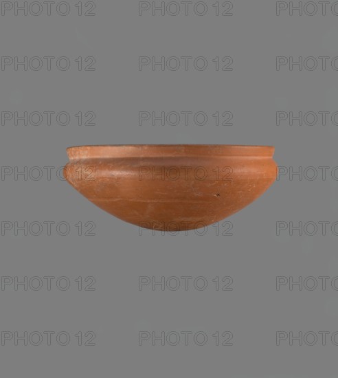 Medum-type bowl, Medum-type bowl with characteristic carination under the rim. Rounded bottom. Straight, slightly flaring rim. Narrow, sloping shoulders. The diameter of the rim is smaller than the diameter of the vessel's shoulders. Nile clay, light red, well fired. Surface leveled, covered with a layer of engobe and then polished. On the outside of the bottom part is a hieroglyphic sign in the shape of a bird, probably the letter m. Vessel color red. The vessel is complete, very well preserved. Old Kingdom, ca. 2686–2181 BC. Vessel: height 8.9 cm; diameter 20.9 cm rim; diameter 21.5 cm shoulders., A terracotta bowl with a rounded base and a slightly flared rim, shown against a flat gray background; the bowl is an earthy reddish-brown with lighter worn areas and subtle surface scratches, and there are a few small darker spots on its exterior.