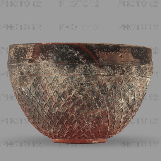 Megarian bowl, unknown Ionian workshop, end of 2nd–beginning of 1st century BC, Ionia Turkey/Greece, classified Gallic scenography; vessel height 8.5 cm, width 13.1 cm, weight 0.178 kg., A rounded bowl with a textured surface showing a repeating raised diamond pattern on its lower portion and a rougher band with pebble-like texture near the rim, colored in shades of reddish brown, dark brown, gray, and areas of pale off-white weathering, sitting against a plain gray background.
