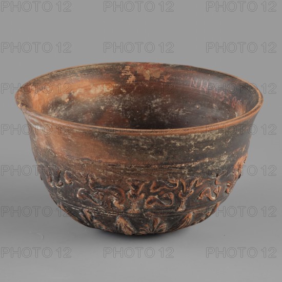 Megarian bowl, KIPBEI workshop, 2nd half of the 2nd century BC, Smyrna, vessel, Megarian bowl, weight 0.120 kg, A ceramic bowl with a rounded shape and a slightly flared rim, showing a worn surface in shades of brown, reddish-brown, black, and gray; the interior shows mottled patches of reddish-brown and darker brown with areas of lighter abrasion, while the exterior has darker blackened areas and reddish-brown highlights; a decorative band with raised, curving, organic relief motifs wraps around the lower exterior in darker brown and reddish tones; the rim edge and inner lip display lighter reddish-brown wear; the background is a uniform gray.