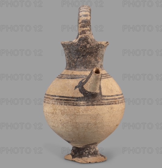 Jug, Jug on a ring-shaped foot from which a low, wide stem extends, transitioning into a belly. The upper part of the spherical body has a narrow spout. The wide, flaring neck terminates in a simple spout, from both sides of which a vice shaped like a flattened cylinder extends above the vessel. Decoration in brown varnish: concentric circles around the vessel four below and three above the spout. The foot and stem are varnished on top; the neck and outer side edges of the vice are varnished. The upper part of the vice is decorated with a row of transverse stripes. A strip of varnish encircles the spout at the base, and three stripes decorate the spout on the sides and top. Dated 1050–950 BC; Cyprus, Geometric Period I District IA. Vessel. Height 12.8 cm; width 6.5 cm., A rounded ceramic vessel with a narrow neck, a flared lip, a single curved handle arching from the lip to the neck, and a short spout protruding from the shoulder; the body sits on a small foot. The surface shows a beig...