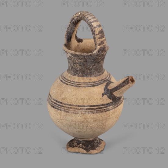 Jug, Jug on a ring-shaped foot with a low, wide stem leading to a belly. Upper part of the spherical body has a narrow spout. Wide, flaring neck terminates in a simple spout; from both sides of the neck a lug shaped like a flattened cylinder extends above the vessel. Decoration in brown varnish: concentric circles encircling the vessel four below and three above the spout. Foot and stem varnished on top; neck and outer side edges of the lug varnished. Upper part of the lug decorated with a row of transverse stripes. A band of varnish encircles the spout at the base; three stripes decorate the spout on the sides and top. Dated 1050–950 BC; Cyprus, Cyprus–Geometric I District IA. Vessel. Height 12.8 cm; width 6.5 cm., An aged pottery vessel with a round body, narrow neck, and a curved handle that arches from the neck to the rim, featuring a short spout protruding from the shoulder; the surface shows bands of darker painted decoration and weathered, rough areas, with visible wear and smal...