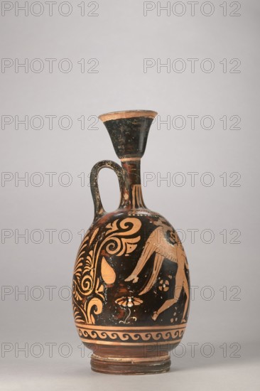 Red-figure aryballus lekythos with a depiction of Eros and a woman, Darius Painter active 340–320 BC, Apulia, 340–320 BC; vessel lekythos, aryballus lekythos, height 23.3 cm, width 10.7 cm., A ceramic vessel with an elongated neck and a flared rim sits against a neutral background; it has a single curved handle connecting neck and shoulder and a rounded body rising from a stepped foot. The surface shows contrasting bands of dark black and warm terracotta tones with ornamental painted motifs, including swirling foliate patterns, stylized palmette forms, and parts of a winged figure rendered in the terracotta color against the black ground. The neck and handle show wear with patches where the dark pigment is worn, and a decorative band of wave-like meanders encircles the lower body above the foot. The visible colors are black, terracotta, and hints of lighter worn beige.