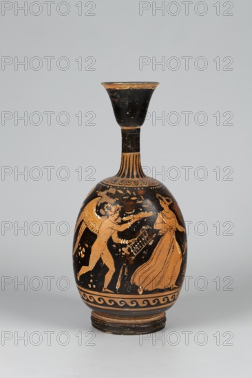 Red-figure aryballus lekythos depicting Eros and a woman, attributed to the Darius Painter active 340–320 BC, Apulia, 340–320 BC; vessel lekythos, aryballus lekythos, height 23.3 cm, width 10.7 cm., A rounded ceramic vessel with a narrow neck and flared mouth sits against a light gray background; the vessel's surface shows a palette of black and orange with areas of worn brown. The body features an orange-figured scene on a black field depicting a winged figure reaching toward a draped standing figure, both rendered in orange with black detailing; decorative bands and a wave-like border encircle the base in orange and black, and the neck shows alternating vertical orange and black stripes leading to a largely black flared rim that has worn orange edges.