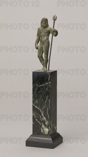 Figurine of Poseidon, unknown Roman workshop. Figurine of Poseidon standing in contrapposto, resting on a trident. The weight of the body rests on the left leg; the right is slightly moved back, the foot bent at the toes. The body is nude, correctly modeled, with clearly defined abdominal muscles. In the left hand the figure holds a trident; the right hand is lowered at the side of the body, holding a cylindrical object at hip level. The head is slightly bowed. The face is framed by long hair and a beard. 1st century, Roman Empire 27 BC–476. Figurine; height 8.7 cm, width 3.5 cm, depth 1.8 cm, weight 0.362 kg with base., A small greenish bronze figurine of a bearded male figure stands on a tall dark pedestal; the figure has a weathered green and brown patina and holds a long thin staff topped with a three-pronged element, with one arm bent and the other relaxed, and the figure stands with a slight contrapposto. The pedestal is a tall rectangular block of dark greenish-black marble with...