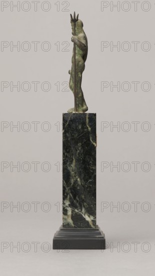 Figurine of Poseidon, unknown Roman workshop. Figurine of Poseidon standing in contrapposto, resting on a trident. The weight of the body rests on the left leg; the right is slightly moved back, the foot bent at the toes. The body is nude, correctly modeled, with clearly defined abdominal muscles. In the left hand the figure holds a trident; the right hand is lowered at the side of the body, holding a cylindrical object at hip level. The head is slightly bowed. The face is framed by long hair and a beard. 1st century, Roman Empire 27 BC–476. Bronze figurine, height 8.7 cm, width 3.5 cm, depth 1.8 cm, weight 0.362 kg with base., A small sculpted figure stands on a tall rectangular pedestal; the figure has a greenish patina with darker and lighter mottling and holds a long staff topped with a three-pronged shape, the staff appearing darker brown; the pedestal is a dark green and black mottled stone with lighter veining and sits on a stepped black base; the background is a smooth light gr...